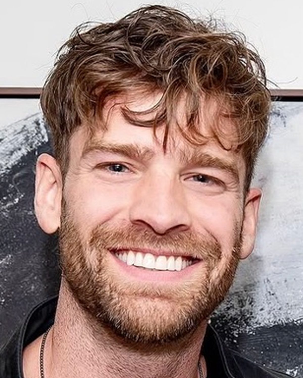 Francois Neron, smiling, in front of a painting.